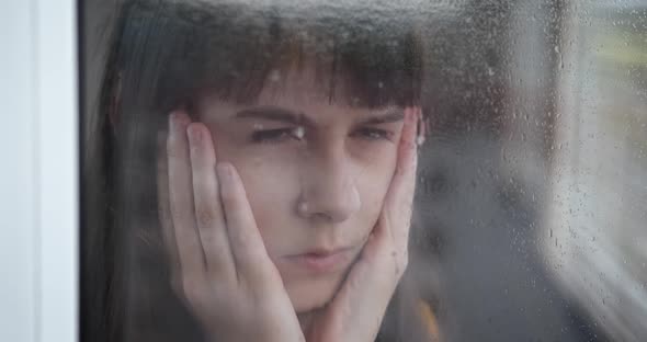 Teen by rainy window.