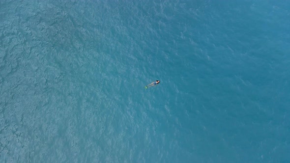 overhead view of woman in flippers swimming in blue water