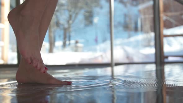 Close-up of a woman stepping into a pool at a luxury spa resort.