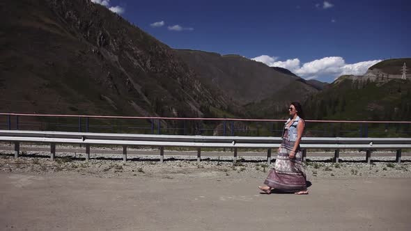 Beautiful Girl Walks on the Road in the Mountains Straightening Her Hair