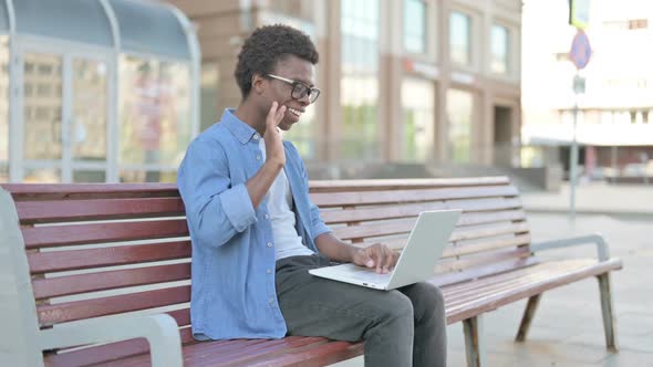 Young African Man Talking on Video Call While Sitting Outdoor on Bench