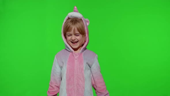 Little Blonde Child in Unicorn Costume Crying Wiping Tears with Her Hands on Chroma Key Background