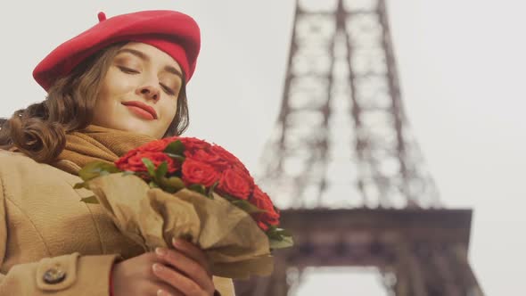 Happy Beautiful Girl Admiring Bouquet Of Red Roses On Background Of Eiffel Tower