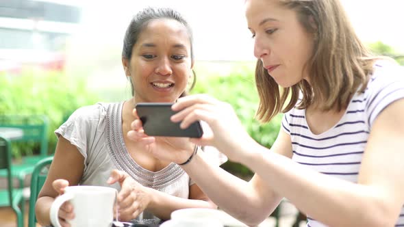 Girlfriends posing for a selfie in outdoor cafe