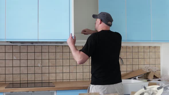 Carpenter working on new kitchen. Handyman fixing a door in a kitchen