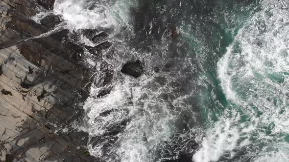 Aerial: waves crashing against rocky coast