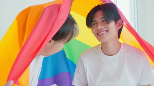 Portrait of Asian handsome man gay family holding LGBT flag and smile.