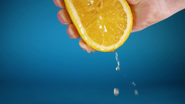 Woman Squeezes Fresh Juice From Lemon on Blue Background
