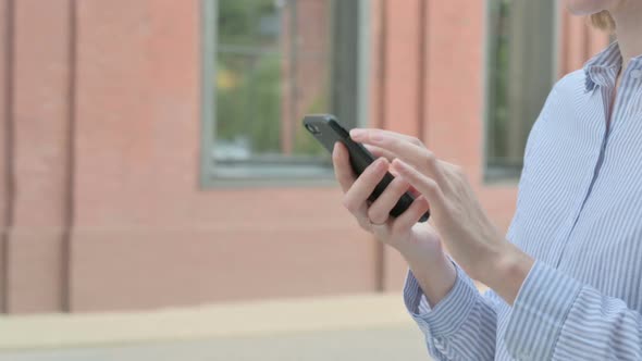 Close Up of Woman Using Smartphone While Walking in Street