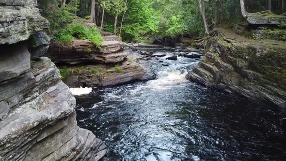 Aerial Up From Water Level in Gorge with Tall Rocky Cliffs