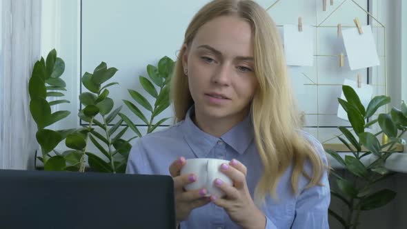 Young Woman Drinking Coffee Working on a Computer at Home Calculating Monthly Exspences Doing Home