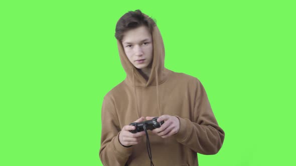Addicted Caucasian Teenager Gaming at Chromakey Background. Portrait of Absorbed Brunette Boy Using