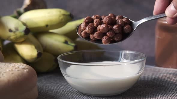 Pouring Chocolate Corn Flakes in a Bowl on Table