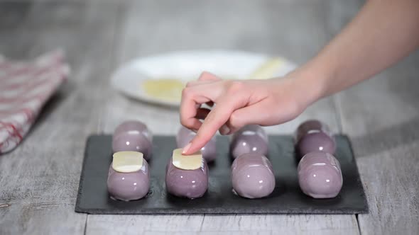 Preparing modern, french desserts - mousse with purple mirror glaze. Decorate french mousse cakes	