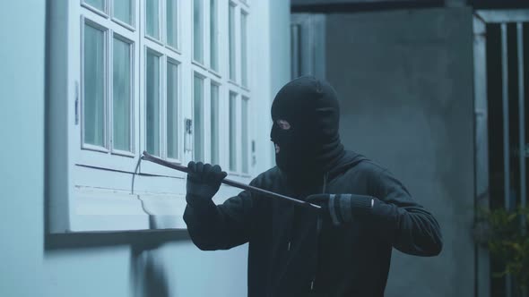 Thief Man Holding Flashlight And Using Crowbar Window The Door Before Entering Someone's House