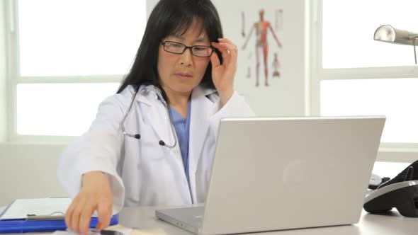 Female doctor reviews laptop computer