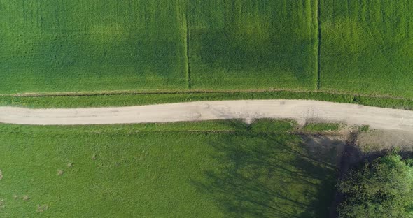 Moving Overhead Over Gravel Paths and Green Fields in Summer Day