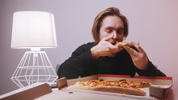 Young Caucasian Man Smiling and Eating Hot Pizza Slice