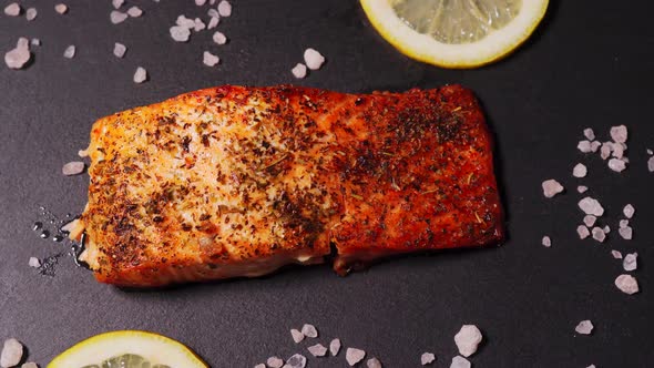 Delicious Baked Golden Salmon on a Black Plate in the Kitchen