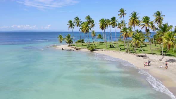 Aerial View as Tourists Walk Along Playa Esmeralda Beach on a Sunny Day, Turquoise Ocean, and Palm T