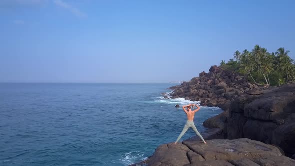 Slim Lady Makes Hair Bun Standing on Large Stone By Ocean