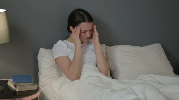 Young Woman with Headache Sitting in Bed