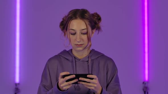 Portrait of Young Attractive Woman Playing a Game on Mobile Phone and Celebrating Victory