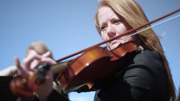 Close up of a woman playing the Violin in an outdoor orchestra