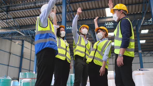 Group of factory or warehouse workers celebrate action or bravo together in workplace area