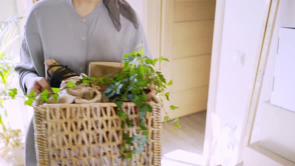 Woman Carries Belongings Basket in Empty Room