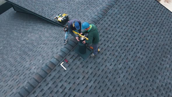 Aerial View of a Two Workers on the Roof Installing the Iron Chimney