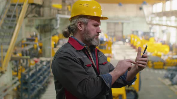 Industrial Worker Using Smartphone in Factory