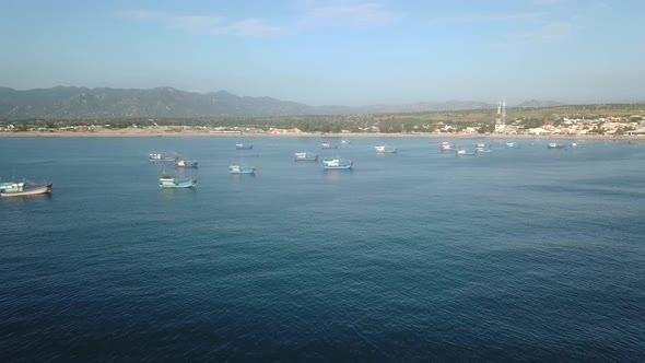 Aerial View of Small Village Shore with Colorful Fishing Boats on Turquoise Ocean.