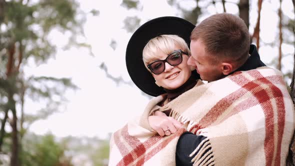 Porait of Couple Covered with Blanket Embracing in Forest