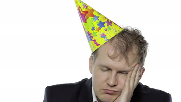 Drunk Sleepy Young Businessman with Hangover in Festive Cap Falling Asleep