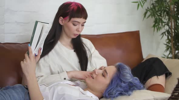 Two Young Lesbian Women are Spending Time Together on Couch in Home Room