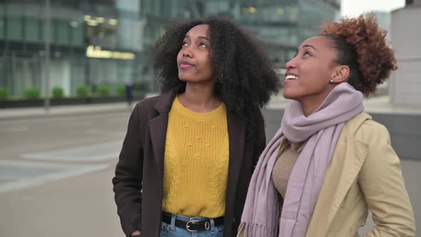 Two women tourists looking at a building in the city where they came as tourists