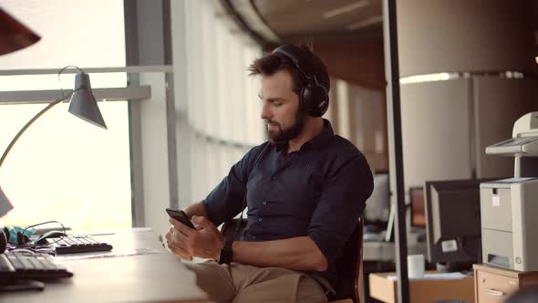 Healthy Stress Free Man Relaxing In Office And Listening To Music. Businessman Leisure In Headphone.