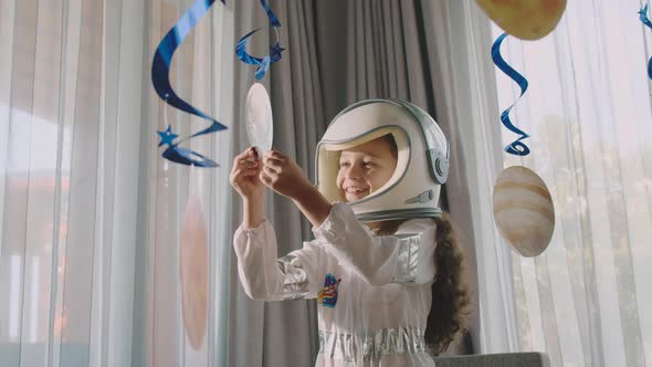 Fantasy Child Astronaut Playing with Suspended Cosmic Planets