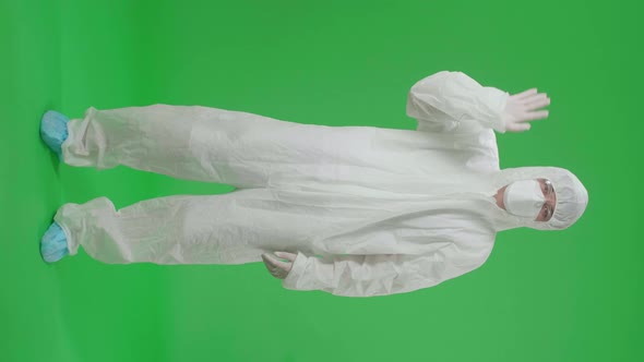 Asian Man Wear Protective Uniform PPE And Waving Hand, Bye Bye In The Green Screen Studio