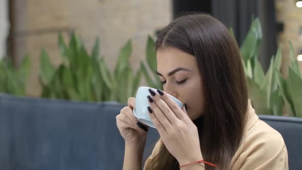 Side View of Confident Young Woman Drinking Coffee From Cup Turning To Camera and Smiling