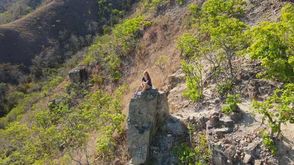 Aerial Shot of a Young Woman Sitting on a Rock in Mountains. Hiking Concept