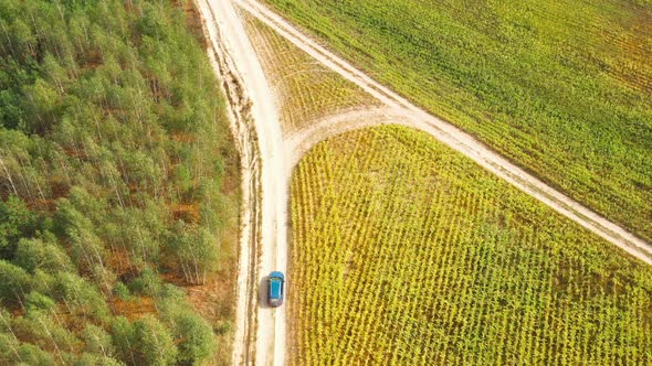 Elevated Aerial View Of Blue Car Vehicle Automobile In Fast Drive Motion On Countryside Country Road