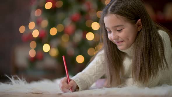 cute little girl lies on the floor and writes a letter to Santa Claus