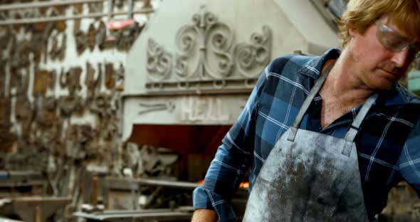 Blacksmith using grinder machine on rod 