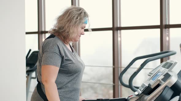 Overweight Woman Exercising on a Treadmill at a Gym