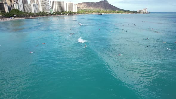 Surfers catch waves at a tropical surfing location as a drone glides above crystal clear blue waters