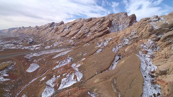 Aerial view of rocky cliffs as road cuts through canyon gorge