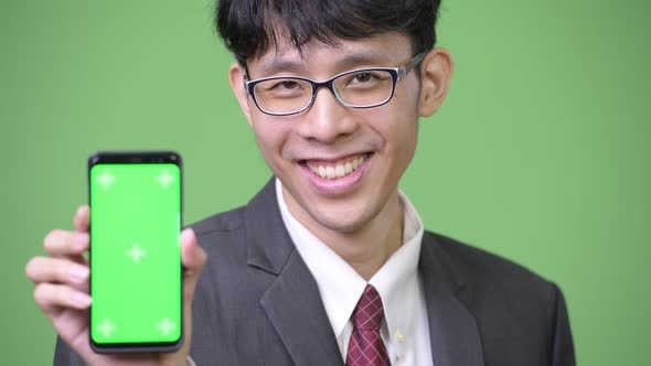 Young Happy Asian Businessman Smiling While Showing Phone To Camera