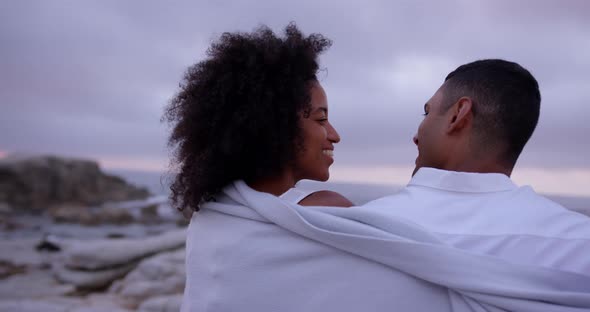 Couple wrapped in blanket on beach 4k